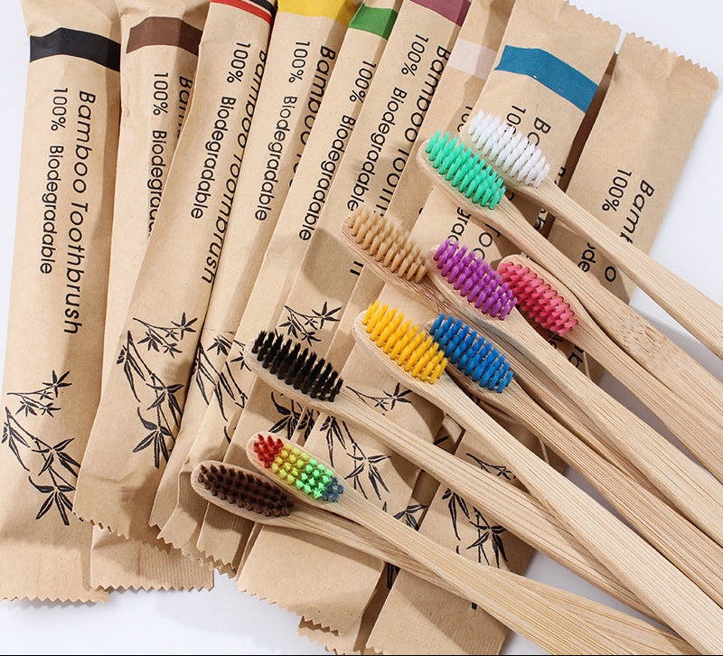 Bamboo toothbrush set in a clear glass holder on a clean bathroom countertop with natural morning light.