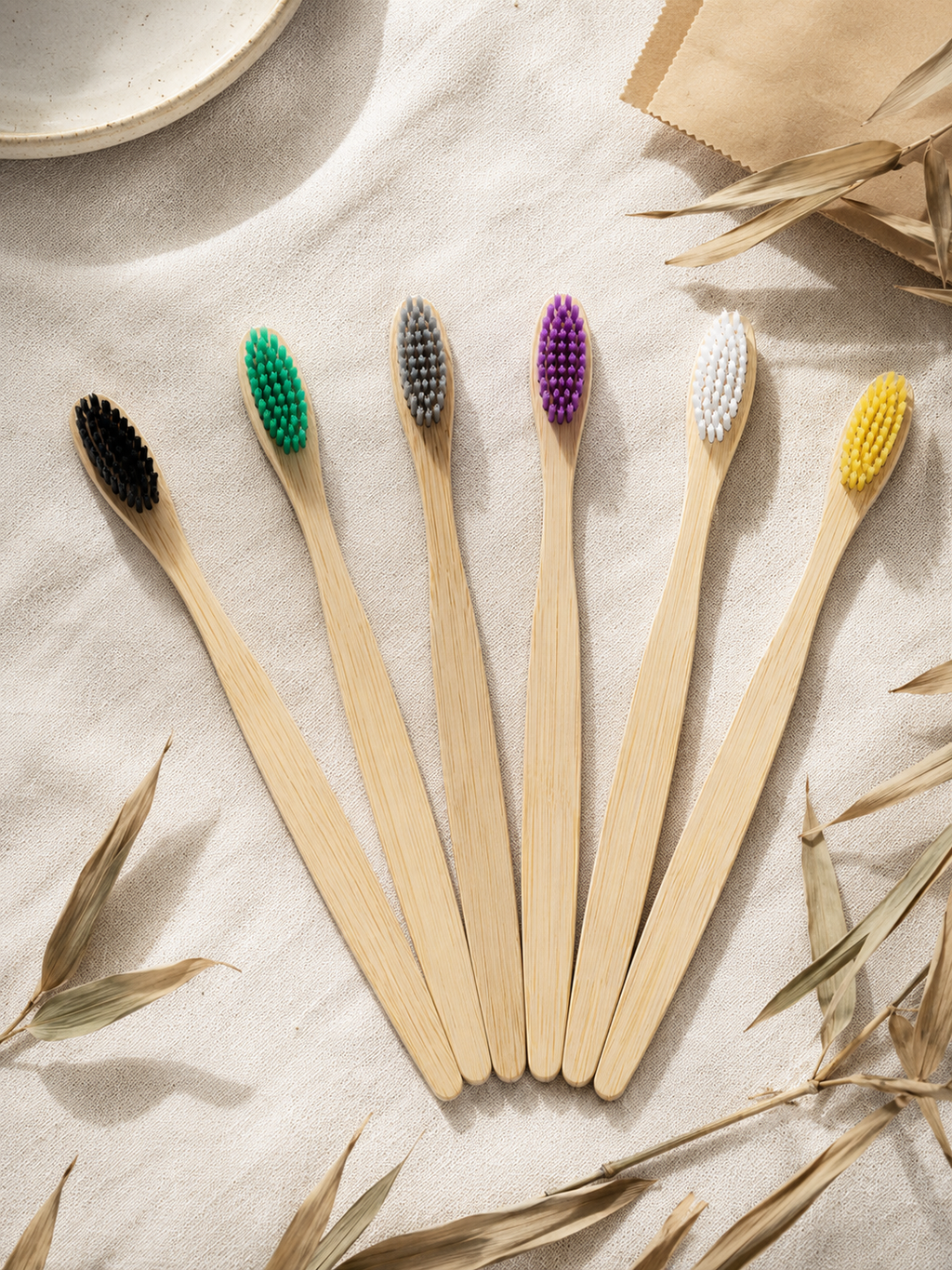 Set of six wooden toothbrushes with colored bristles on a textured surface.